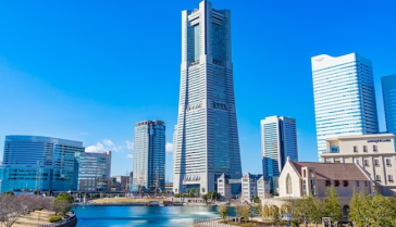 横浜ランドマークタワーを中心としたみなとみらいの都市景観。手前に運河、青空を背景に複数の高層ビルが立ち並ぶ